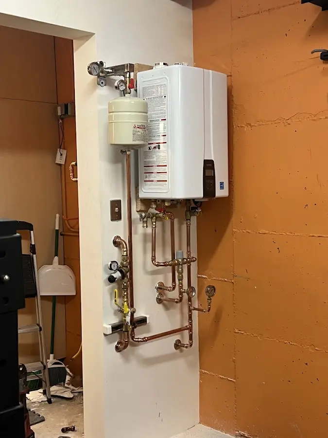 Plumbing technician inspecting water heater connections in Georges